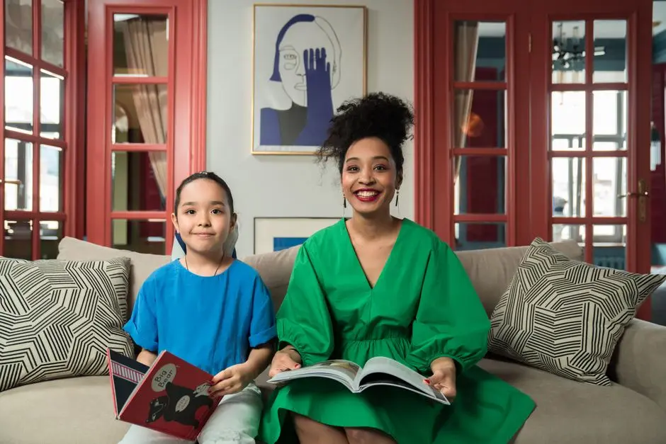 Ibu dan anak sedang membaca buku bersama di ruang keluarga